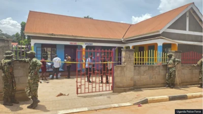 Àwọn ológun dúró sí iwájú ilé ẹ̀kọ́ tí wọ́n ta okùn síwájú rẹ̀, àwọn èèyàn kan wà nínú ọgbà ilé ẹ̀kọ́ náà.