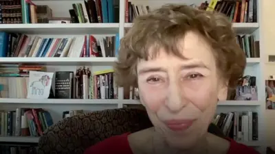 Женщина с короткой стрижкой улыбается на фоне книжных полок