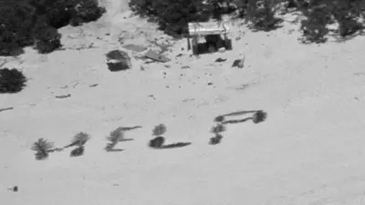 letreto de "Help" escrito en la arena por los 3 hombres perdidos 