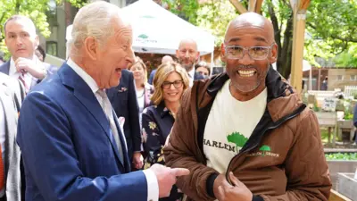 King Charles laughing as he greets peope in New York. Pictured with a happy man who looks at the camera with big smile. 