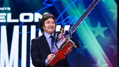 Javier Milei sonriendo mientras sostiene una motosierra en las manos.