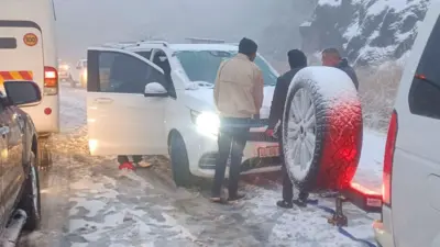 People trying to free their car stuck in heavy snowfall