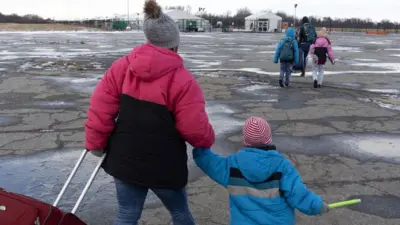 Migrant families come and go from the Floyd Bennett Field migrant shelter on December 25, 2024, in the borough of Queens, New York City