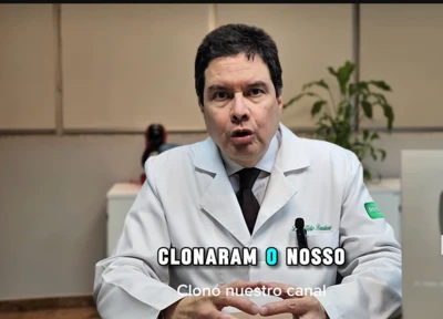 Imagem do médico Hélio Brasileiro de jaleco, falando com um microfone para uma câmera, em formato de vídeo de depoimento, com placa do Youtube ao lado