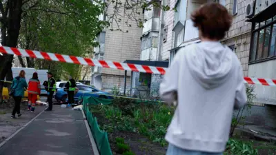 Хлопець в білій кофті дивиться на місце злочину, огорджене стрічкою поліції