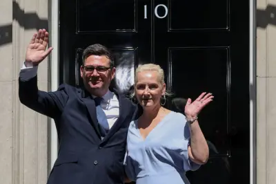 Nagy-Britannia újonnan kinevezett miniszterelnöke, Andy Burnham integet a londoni Downing Street 10. előtt feleségével, Marie-France van Heellel, miután hivatalba lépett, 2026. július 20-án.