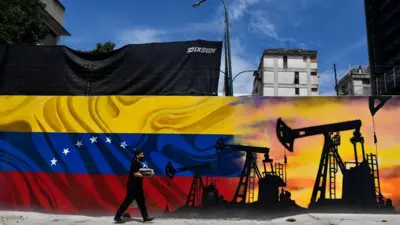 Un hombre con una mascara pasa por un mural con la bandera de Venezuela y algo unos balacines de petróleo. (Photo by Federico PARRA / AFP)