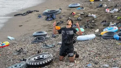 Migrantes y personas llegadas por vía marítima tras cruzar la frontera entre Marruecos y Ceuta, el 31 de julio de 2026, en Ceuta, España. En la imagen de ve un hombre arrodillado que parece estar agradeciéndole al cielo. 