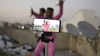 Dos personas que bailan, vistas a través de la pantalla del teléfono que las graba. 
