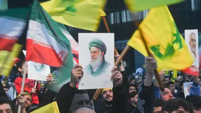 Beyrut'ta düzenlenen bir protesto gösterisine katılanlar, sarı Hizbullah bayrağı ile kırmızı, beyaz ve yeşil İran bayrağının yanı sıra İran İslam Cumhuriyeti'nin Dini Lideri Ayetullah Ali Hamaney'in resimlerini sallarken. 