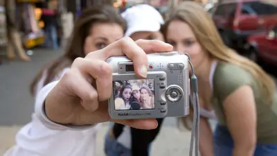 Tres adolescentes se autorretratan con una cámara digital Kodak EasyShare en Times Square.