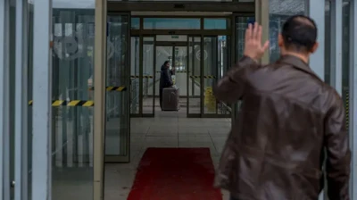 راهرویی در گذرگاه، زنی در حال عبور از گذرگاه، مردی برای او دست تکان میدهد