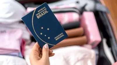 Jovem segurando passaporte brasileiro