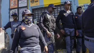 Police cover face, anoda one carry gun.