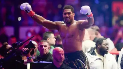 Up on di ropes, Joshua raise im hands and soak for di cheers from di crowd for Jeddah