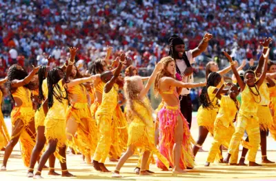 Shakira e o rapper nigeriano Burna Boy cercados por dançarinos no show do intervalo no final da Copa do Mundo