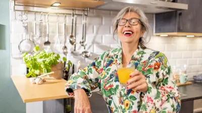 Portakal suyu içerken kahkaha tana bir kadın. Beyaz saçlı.