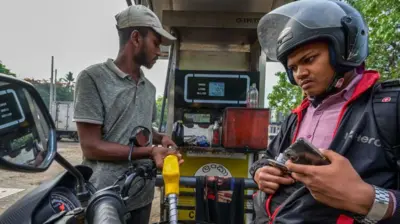 A worker fills petrol in an motorbike at a fuel station 