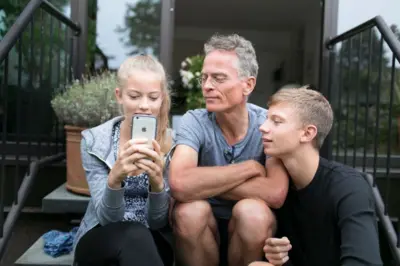 Filhos e pai olhando celular