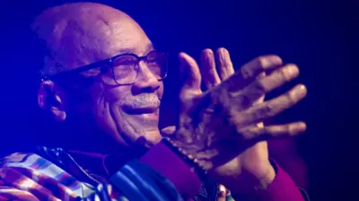 Quincy Jones clapping in the audience and looking at the stage