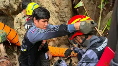 A handout photo made available by Metta Tham Kalasin Rescue shows Thai rescuers on a mission to free seven Laotians trapped in a flooded cave in Xaysomboun province, Laos, 25 May 2026. A rescuer places a protective helmet on the head of another rescuer