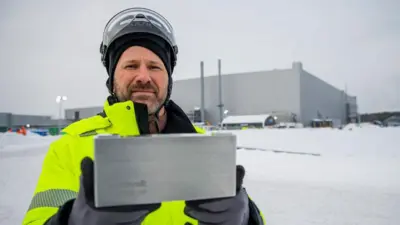 A Northvolt worker holds up a battery outside the Northvolt plant in Skellefteå, Sweden