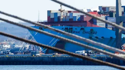  Containers are unloaded from a ship.