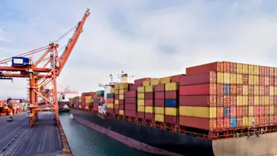 Aerial view of cargo ship with lots of containers on it, docked in a port.