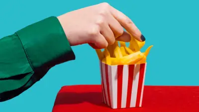 Hand picking French fries from a box