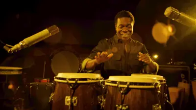 Paulinho da Costa tocando um instrumento durante gravações do documentário