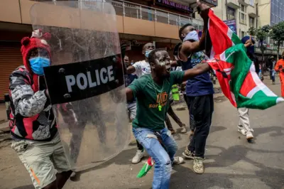 Des manifestants en colère brandissent un bouclier de police et un drapeau kenyan, scandant des slogans (Ruto doit partir) lors d'une manifestation contre les meurtres commis par la police sur des personnes qui protestaient contre le projet de loi anti-fiscalité au Kenya, le 2 juillet 2024 à Nairobi, au Kenya.