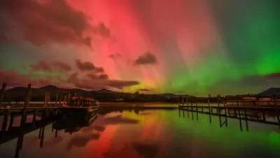 A perfectly still lake reflecting the reds and greens of the aurora display in the sky