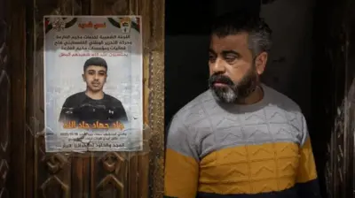 مردی اندوهگین بر در خانهاش ایستاده و نگاهش به سوی آگهی ترحیم پسر نوجوانی است که روی در چسبانده شده