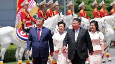 朝鲜领导人金正恩（右二）与其妻子李雪主（右）在平壤金日成广场为中国国家主席习近平举行的欢迎仪式期间，与习近平（左）及其妻子彭丽媛（左二）一同步行。