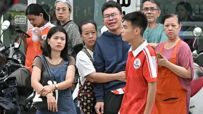 Un grup de persoane, cu expresii îngrijorate, în fața unei școli după un atac armat în districtul Bang Kruai, la nord de capitala Thailandei, Bangkok.