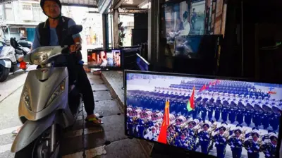 台北街头一位骑着机车的老先生停在一间摆满多台电视机的商店旁,电视机中正直播北京抗战胜利阅兵(3/9/2025)