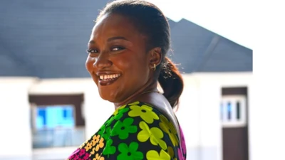 Susan turn face side as she smile dey look camera,