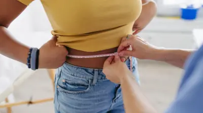 mulher tirando medida da cintura de outra mulher