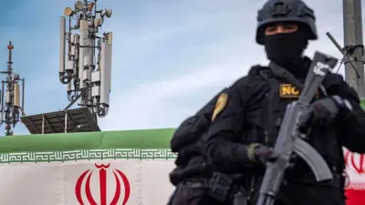 یک مامور نیروهای ویژه با اسلحه درحالی که پشتش پرچم ایران است و کمی دورتر آنتن‌های مخابراتی قراردیده می‌شود