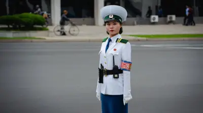 Pyongyang'da bir meydanda beyaz üniformalı bir kadın var. Trafik polisi olduğu anlaşılıyor. Direkt olarak kameraya bakarak gülmeden poz veriyor.