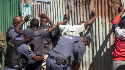 Police arrest gangs for Cape Town on 13 April 2026. Di men raise dia hands while police try to hold dem.