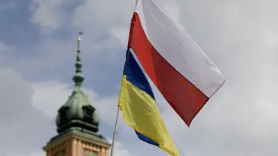 Прапори Польщі та України майорять поруч на тлі історичної будівлі.