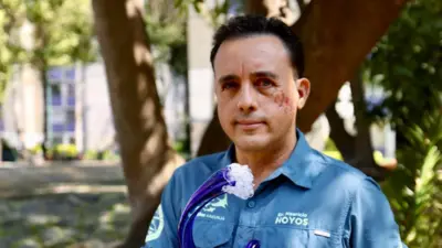 Mauricio Hoyos, dalga şeklindeki bir ödülü tutarken kameraya bakıyor
