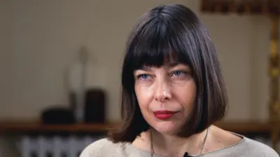 Темноволосая женщина со стрижкой каре смотрит на журналиста