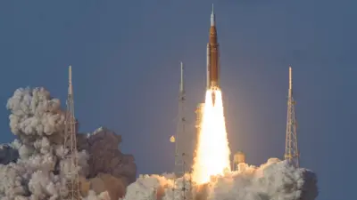 Ракета стартует для полета к Луне, видны клубы дыма и яркий выброс газа из двигателей