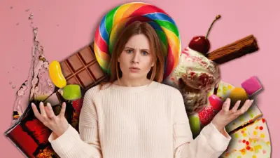 Arkasında renkli tatlılar ve içeceklerle kameraya bakan bir kadın.