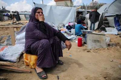 Seorang perempuan Palestina yang terlantar menunggu proses evakuasi setelah Israel melancarkan serangan darat dan udara di wilayah timur Rafah