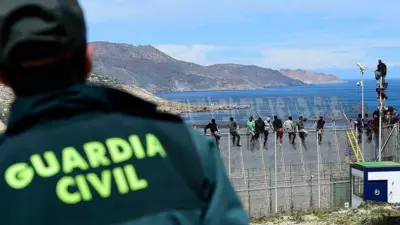 Un agente de la Guardia Civil vigila a migrantes africanos que intentaron escalar la valla en la frontera entre Marruecos y el enclave español norteafricano de Melilla, el 3 de abril de 2014, en Melilla, España.