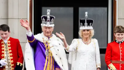 The King and Queen dressed in coronation robes appear on the Buckingham Palace balcony alongside pageboys - including the future king George.