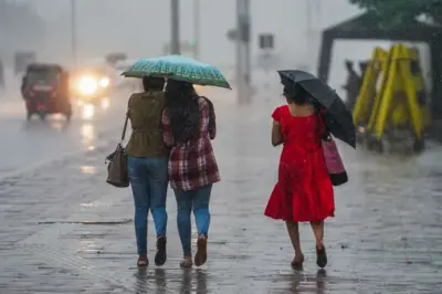 වැස්සේ කුඩ ඉහළාගෙන ඇවිද යන තරුණියන් තිදෙනෙක්